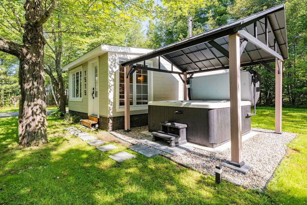 Chalet et spa extérieur sous abri, entouré d'arbres